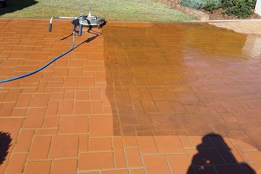 A Person is Cleaning a Brick Patio With a Pressure Washer — AD House Wash & Gutter Cover in East Toowoomba, QLD