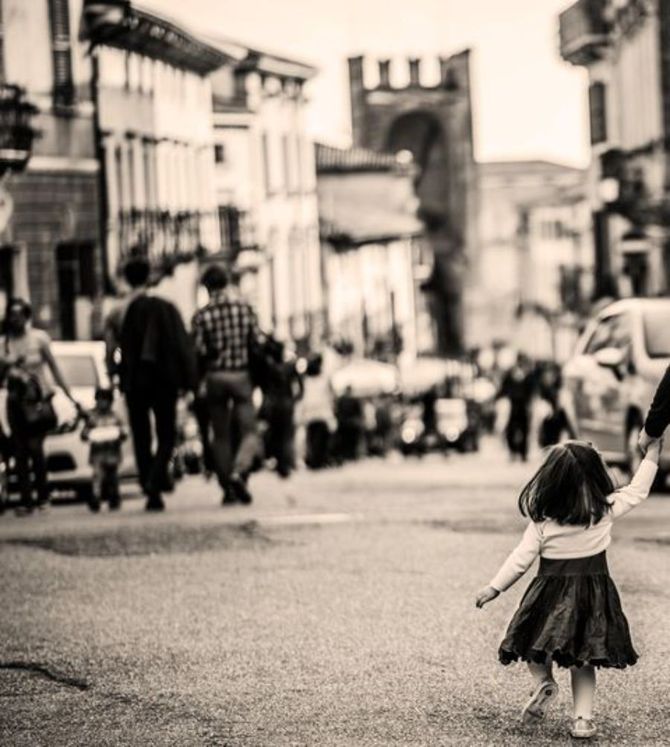 foto di una bambina che tiene la mano al genitore