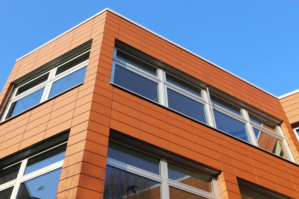 A Large Orange Building With Lots of Windows Against a Blue Sky — Coastal Roofing Professionals In Byron Bay, NSW
