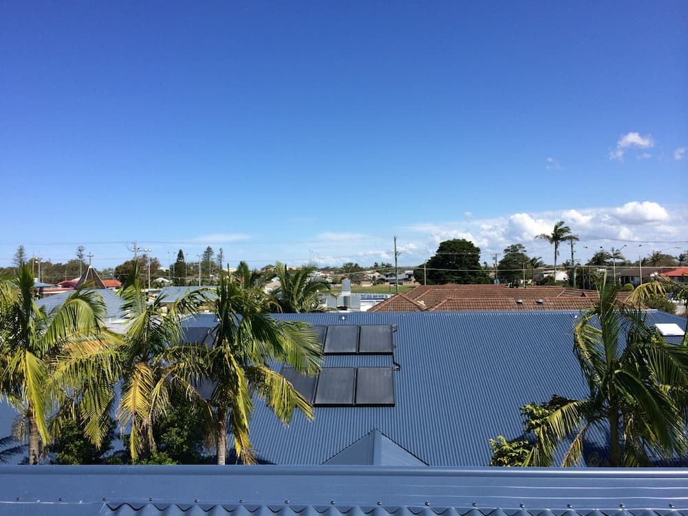 A Rooftop View of a City With Palm Trees and a Blue Sky — Coastal Roofing Professionals In Chinderah, NSW
