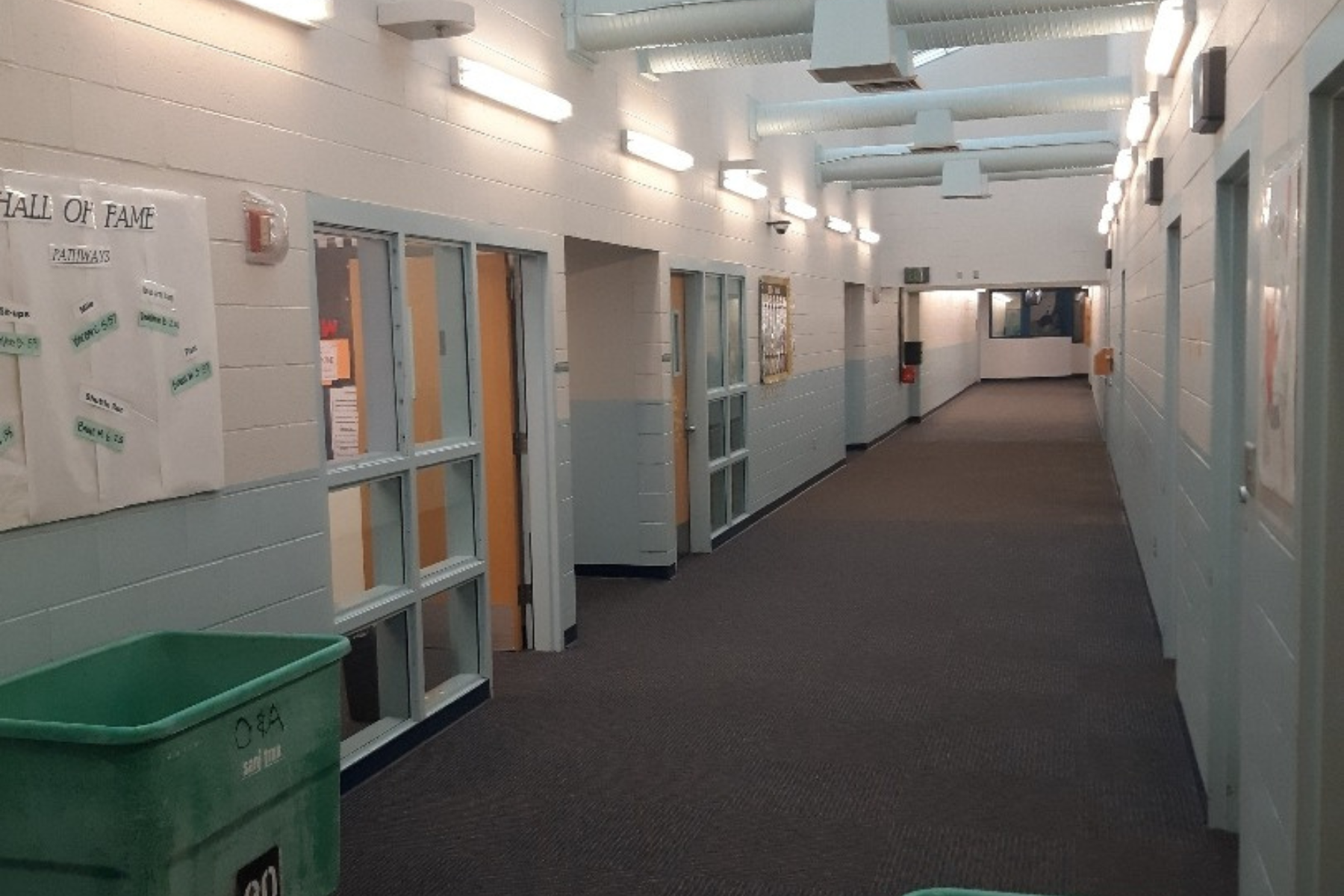 A long hallway with a green trash can in the middle
