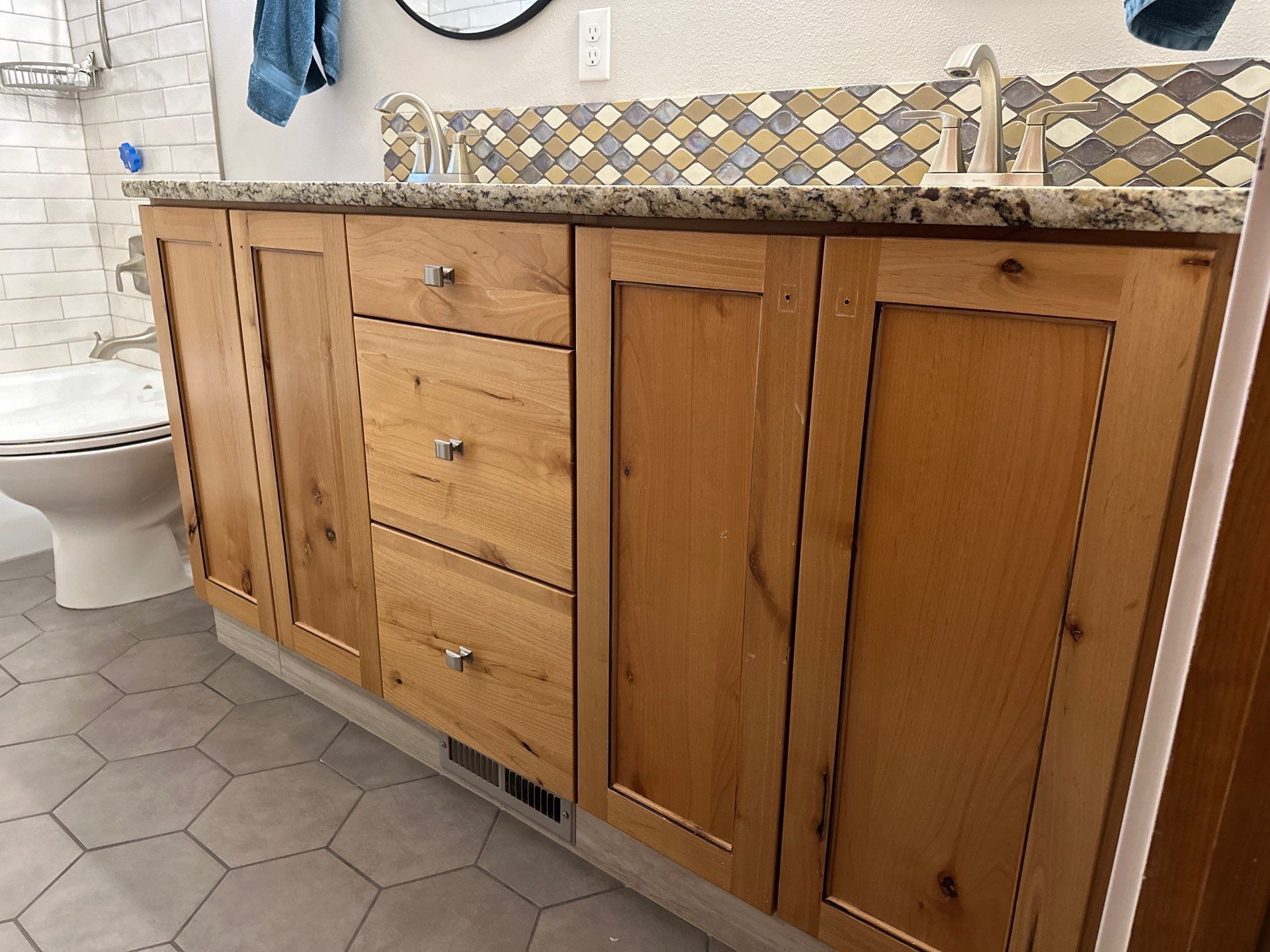 A bathroom with a sink , toilet , and wooden cabinets.