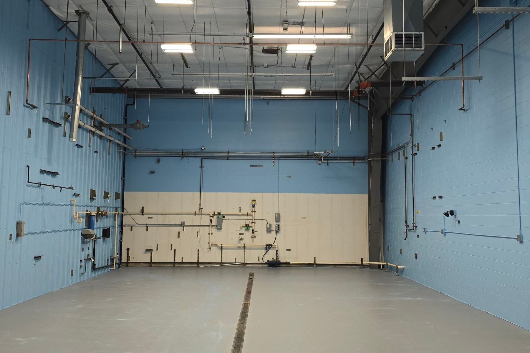 A large empty room with blue walls and gray floors.