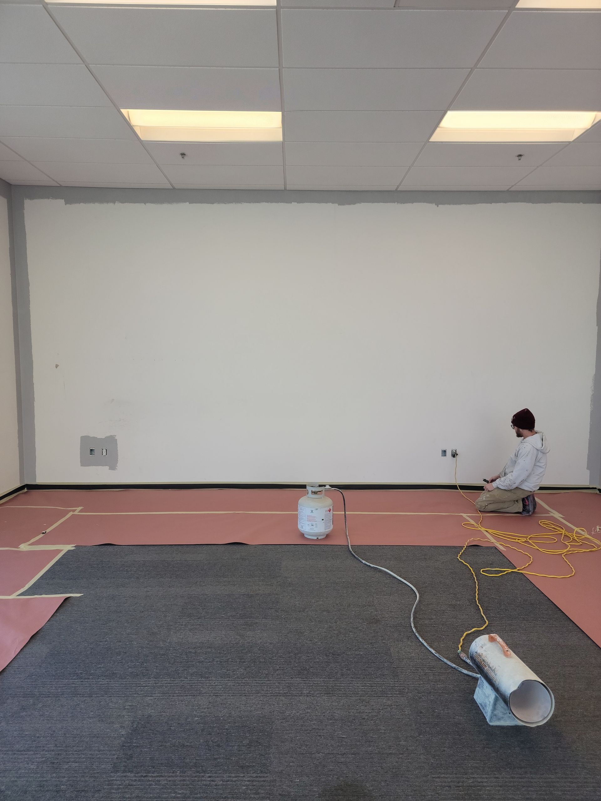 A man is kneeling down in a room with a white wall.
