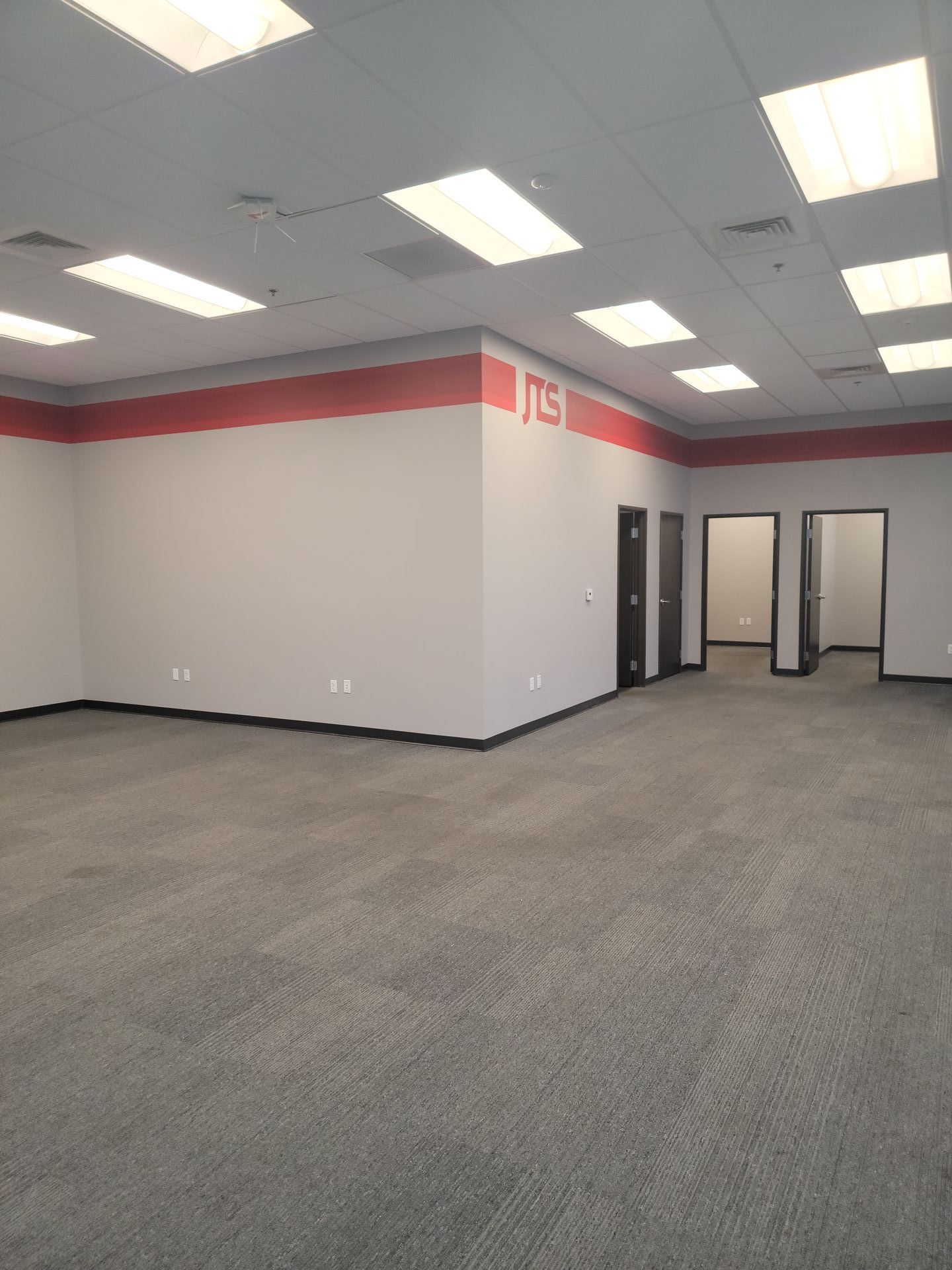 An empty room with a red stripe on the wall that says tcs