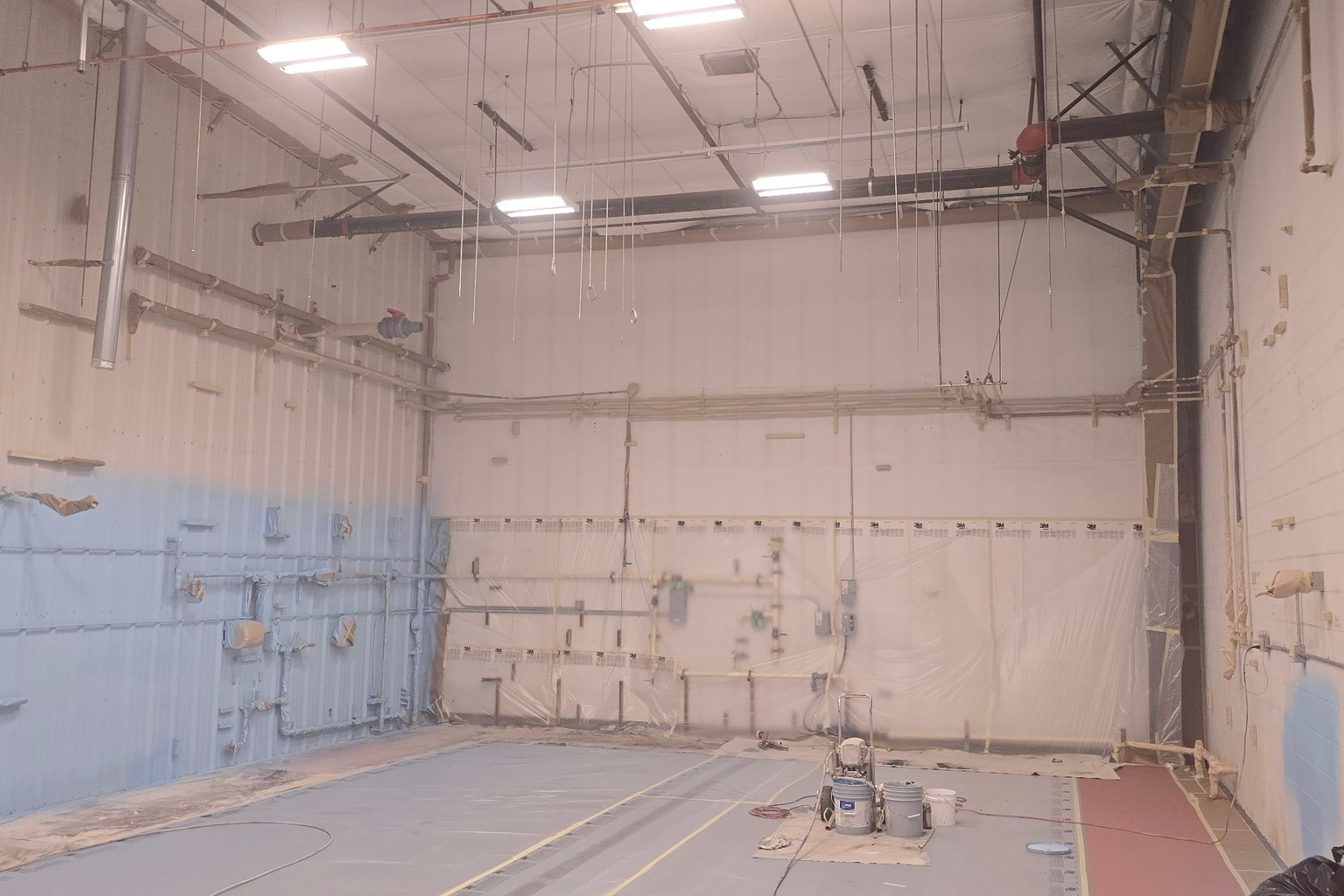 A large empty room with a basketball hoop in the corner.