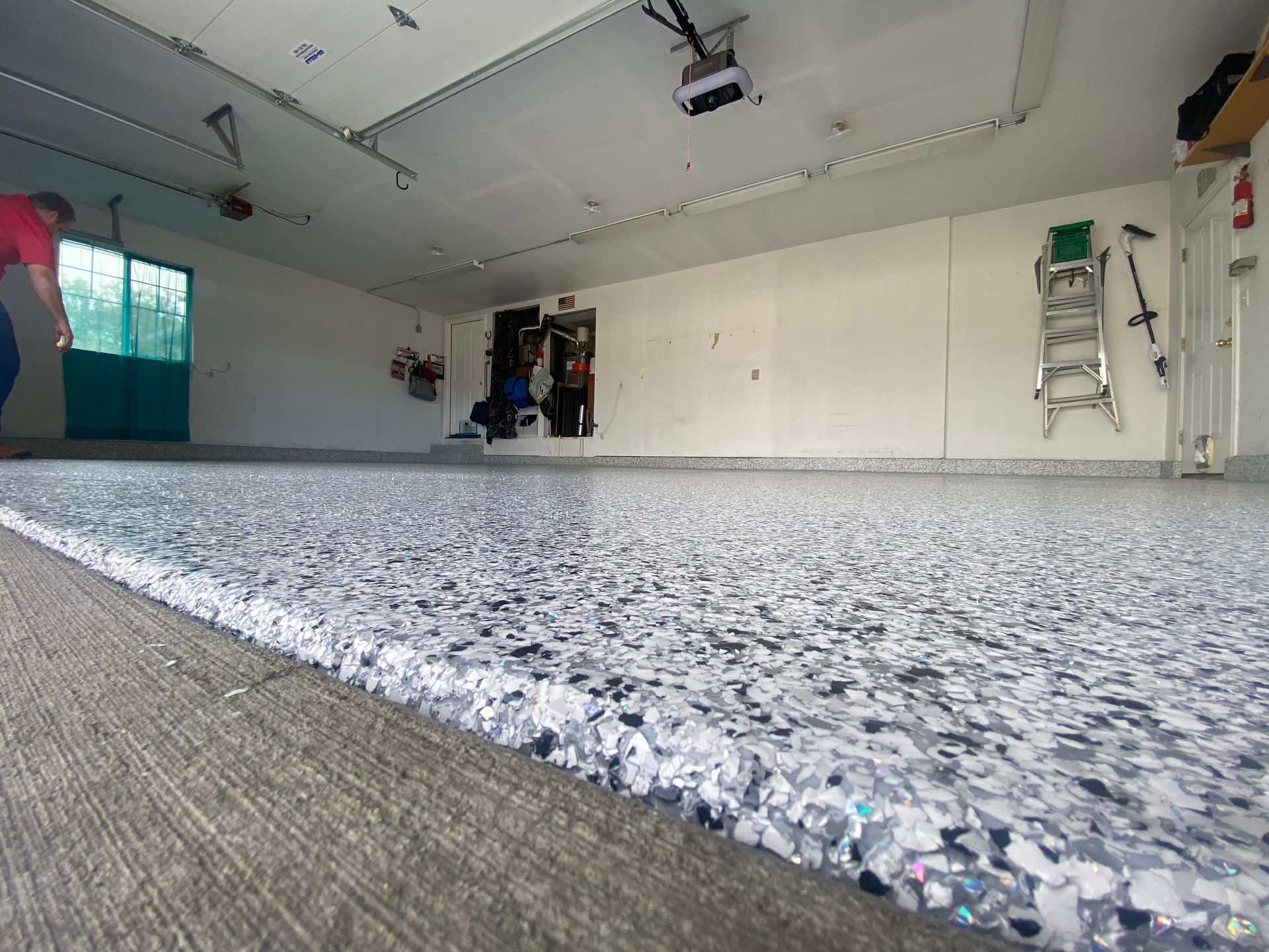 A man is standing in a garage with a concrete floor.