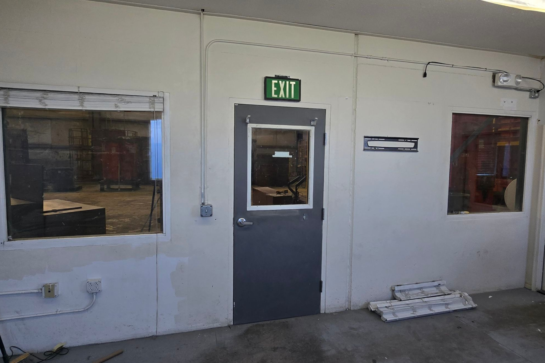 An empty room with a green exit sign above the door
