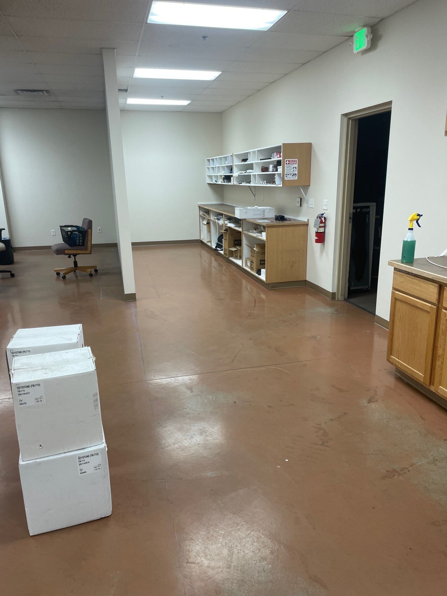 A large empty room with boxes on the floor and cabinets.
