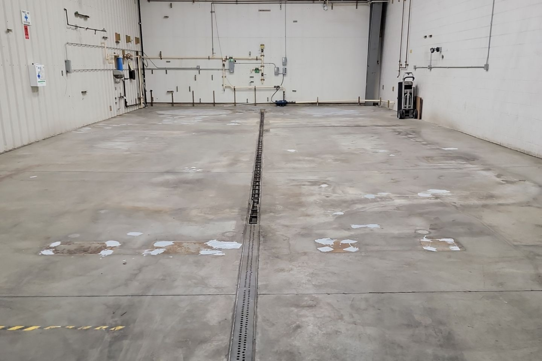 A large empty warehouse with a concrete floor and white walls.