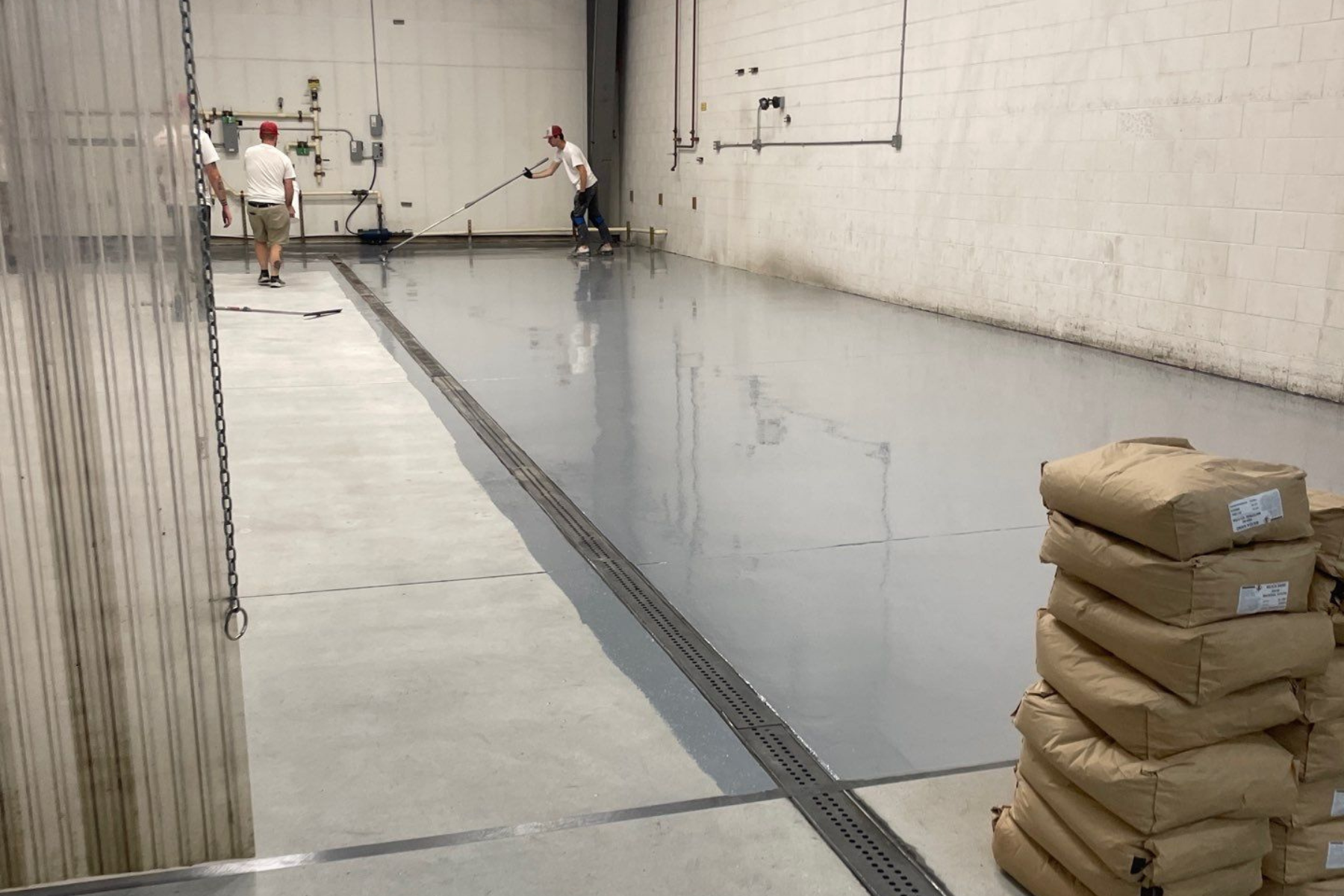 A group of people are working on a concrete floor in a warehouse.