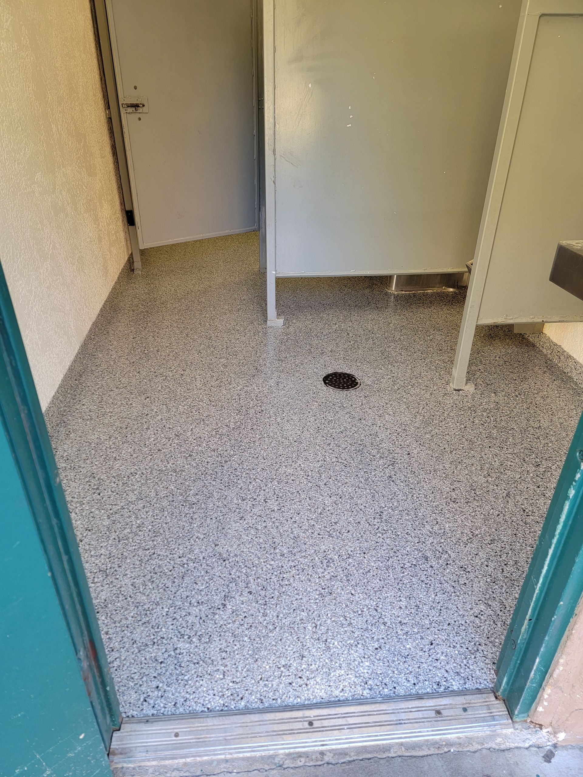 A bathroom with a gray floor and a green door.