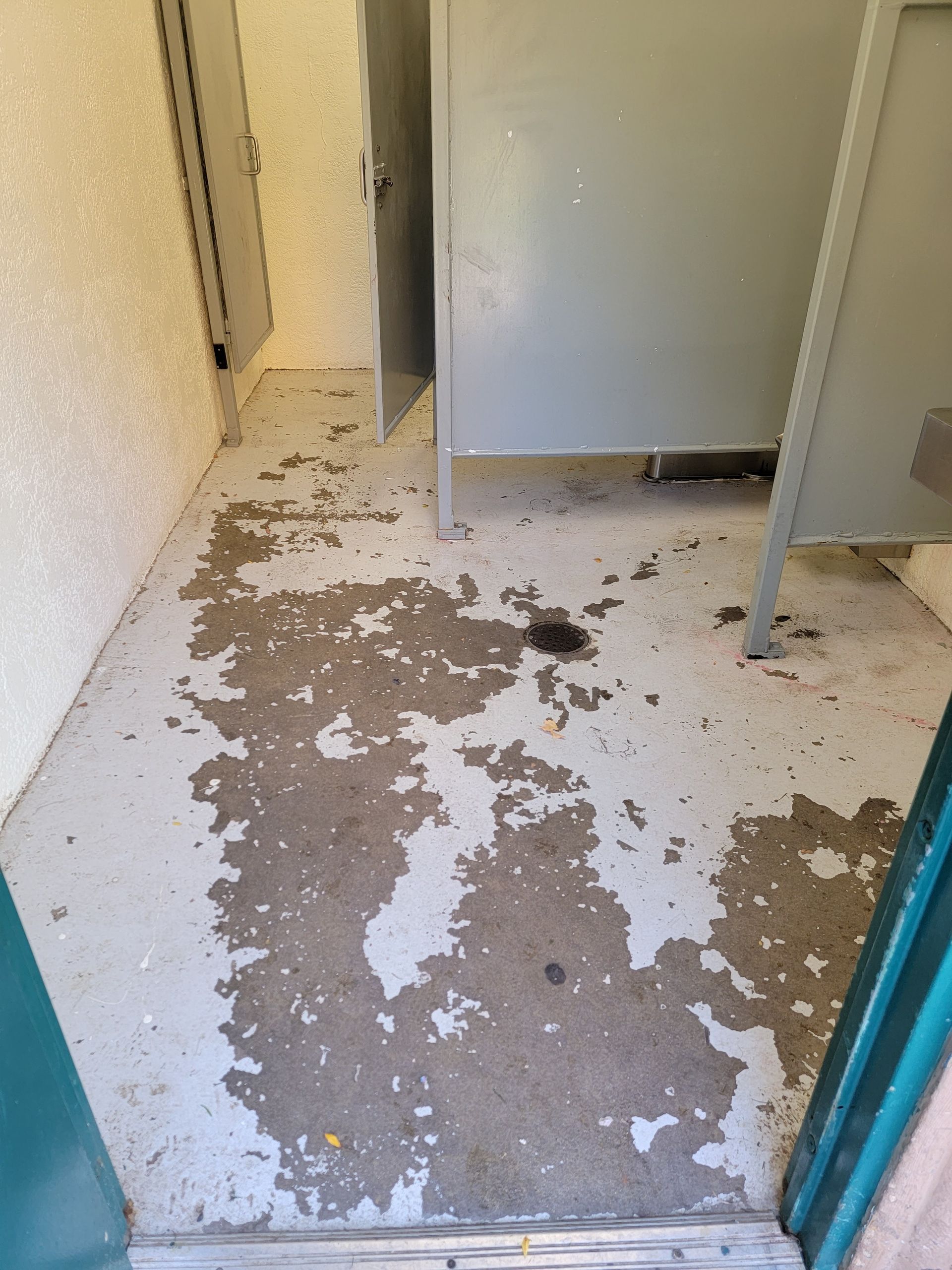 A bathroom with a dirty floor and a door.