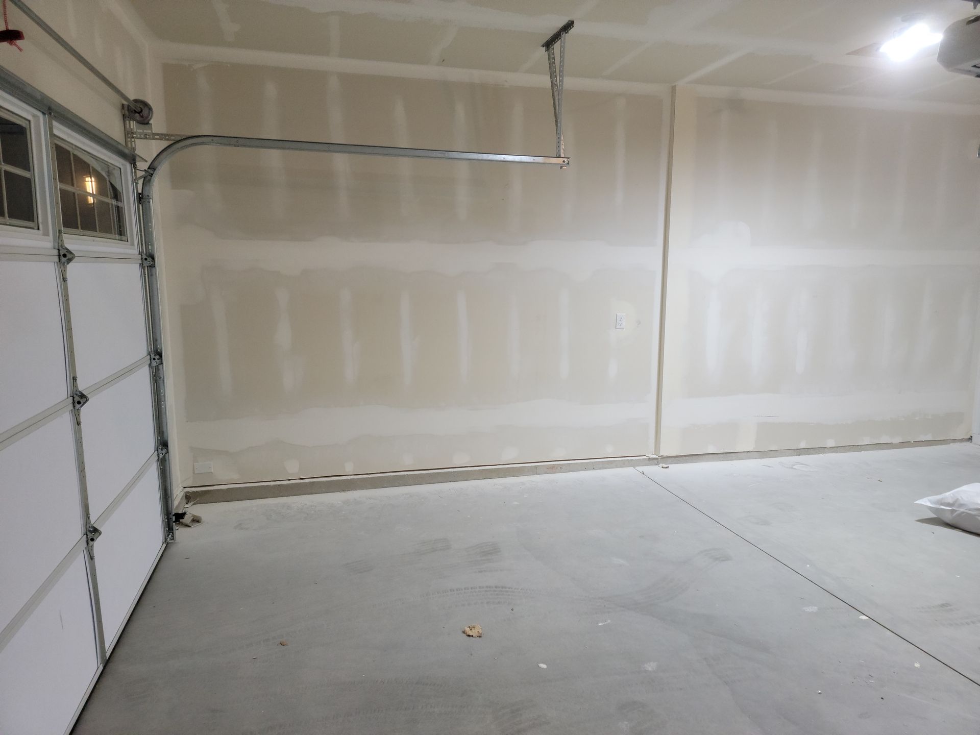 An empty garage with a garage door open and a light on the ceiling.