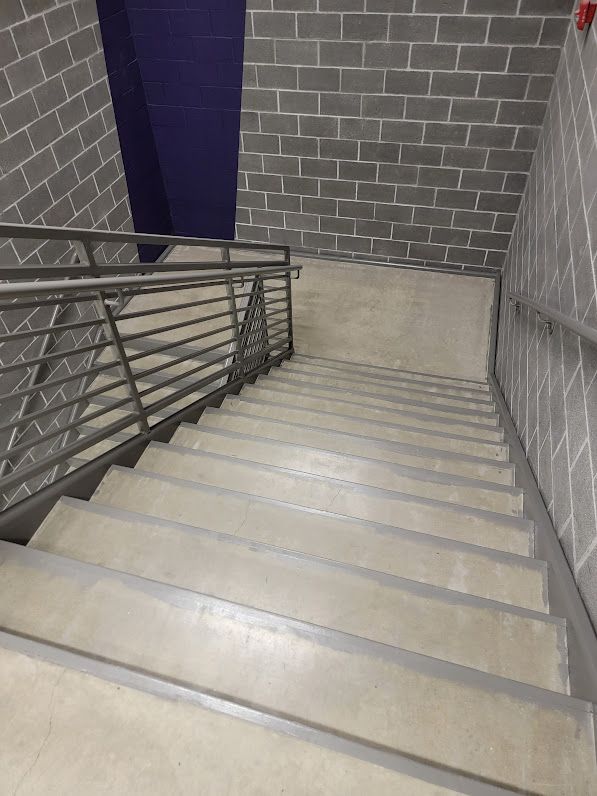 A set of stairs leading up to a brick wall with a metal railing.