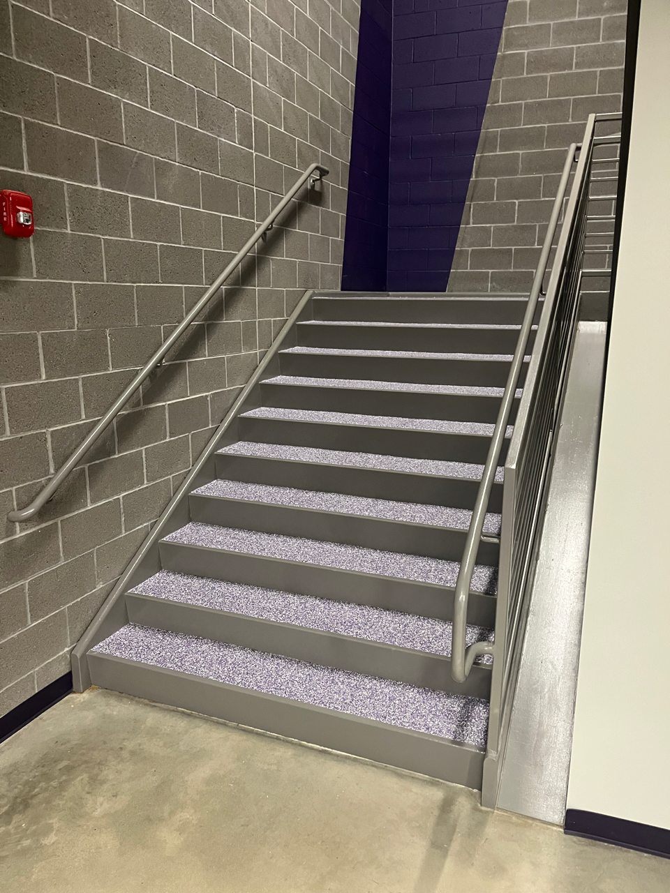 A staircase with a metal railing and a brick wall