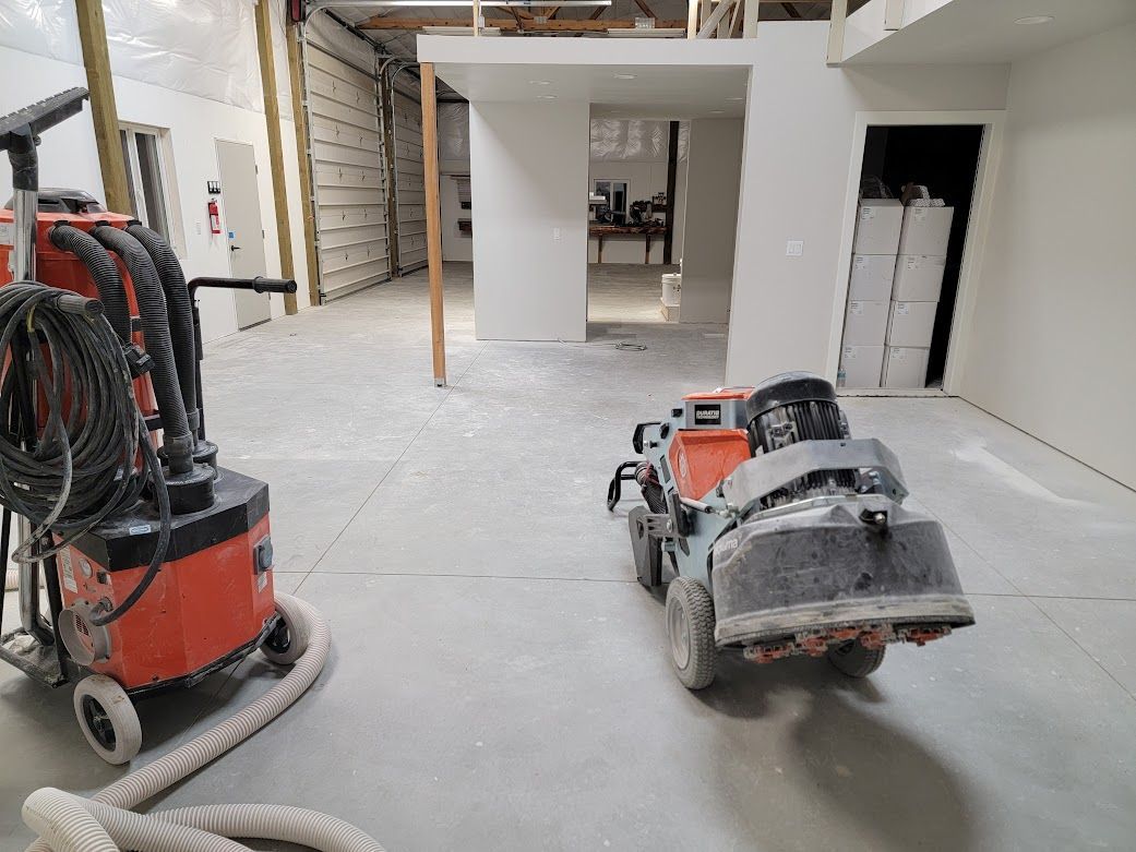 A vacuum cleaner and a concrete grinder are sitting in a room.
