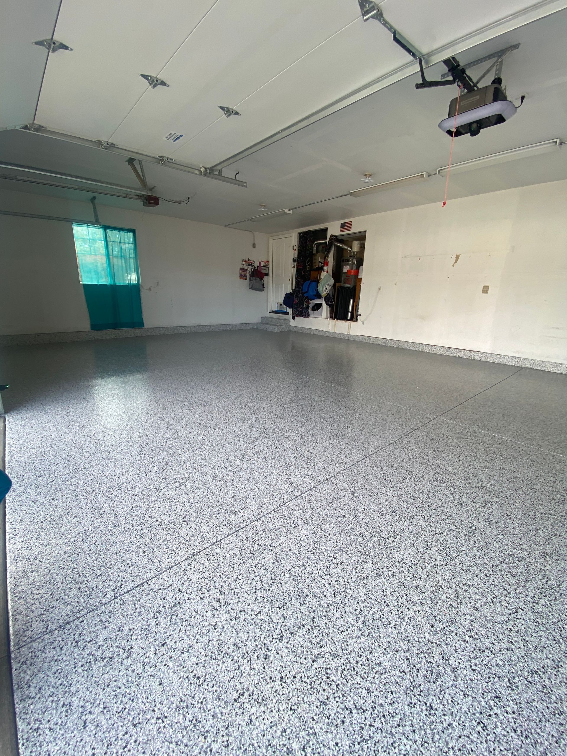 A garage with a garage door open and a gray floor.