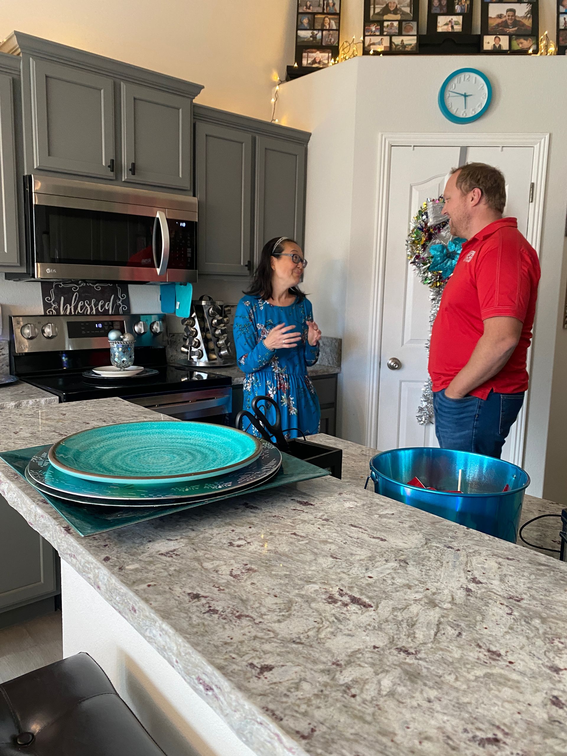 A man and a woman are standing in a kitchen talking to each other.