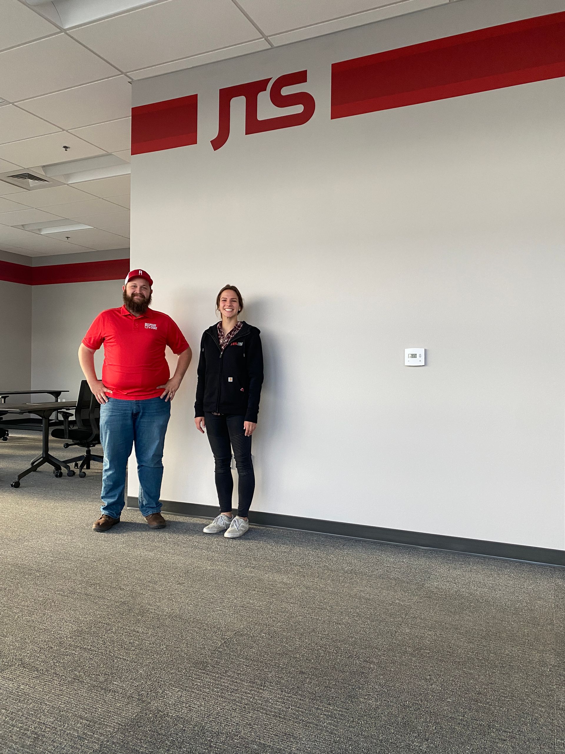 A man and a woman are standing next to each other in an office.