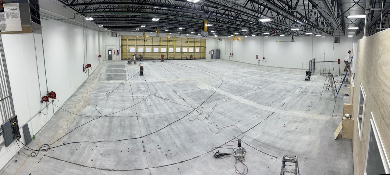 A large empty warehouse with a concrete floor and a yellow door.