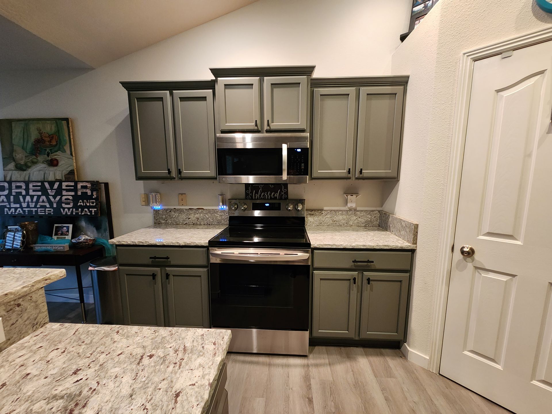 A kitchen with gray cabinets and stainless steel appliances.