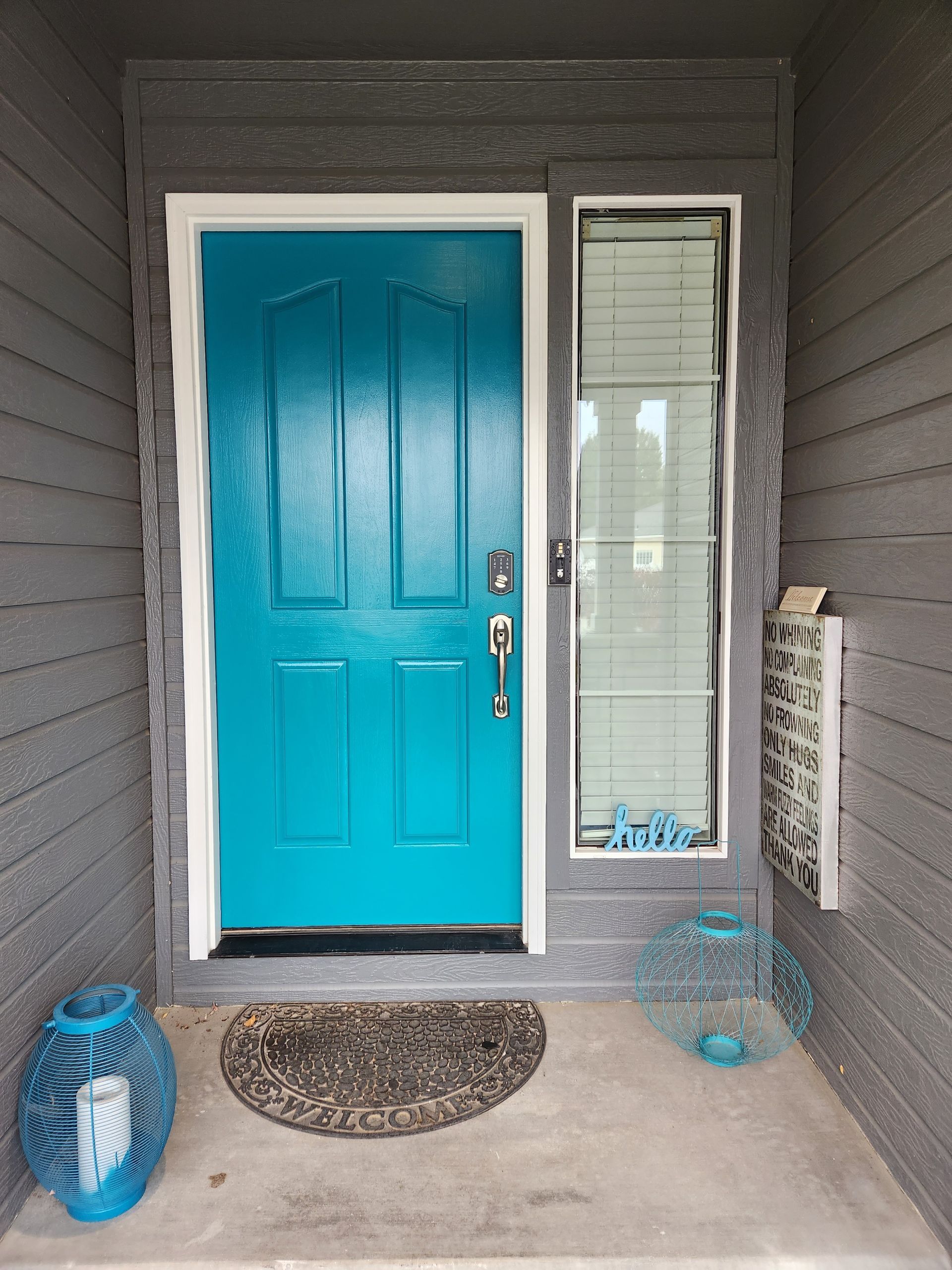 A blue door with a white trim is on a gray house.