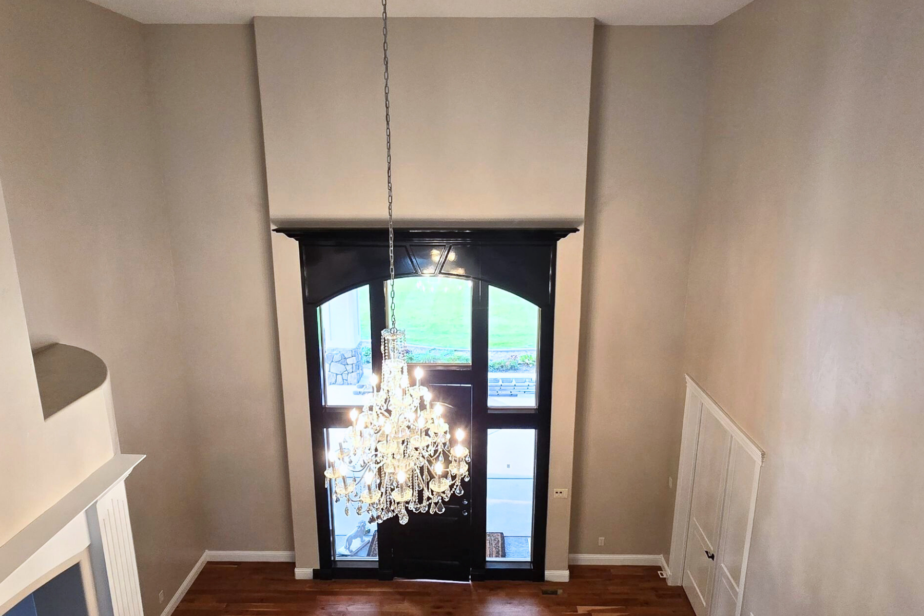 An empty room with a chandelier hanging from the ceiling and a door.