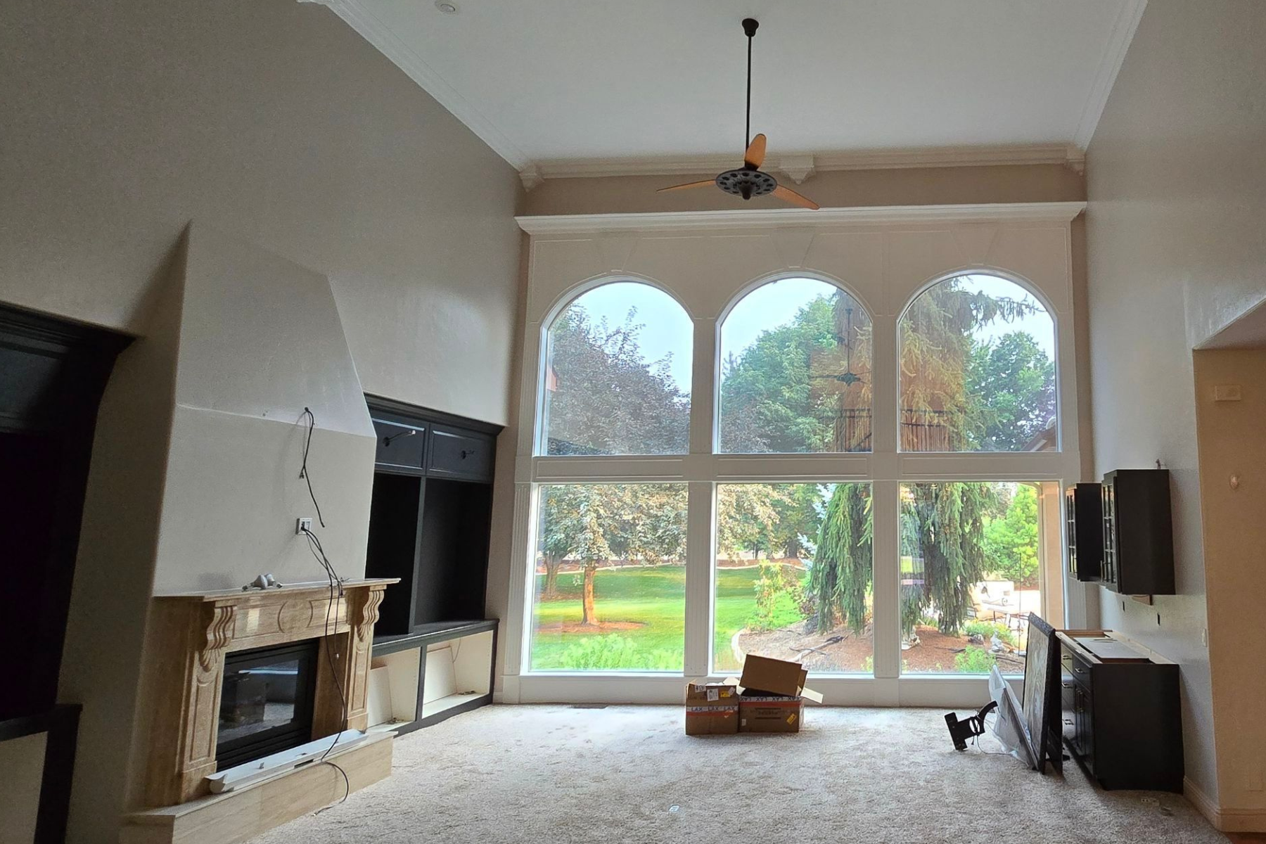 An empty living room with arched windows and a fireplace