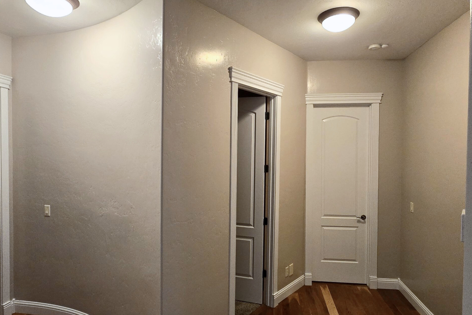 A hallway with a door and a light on the ceiling.