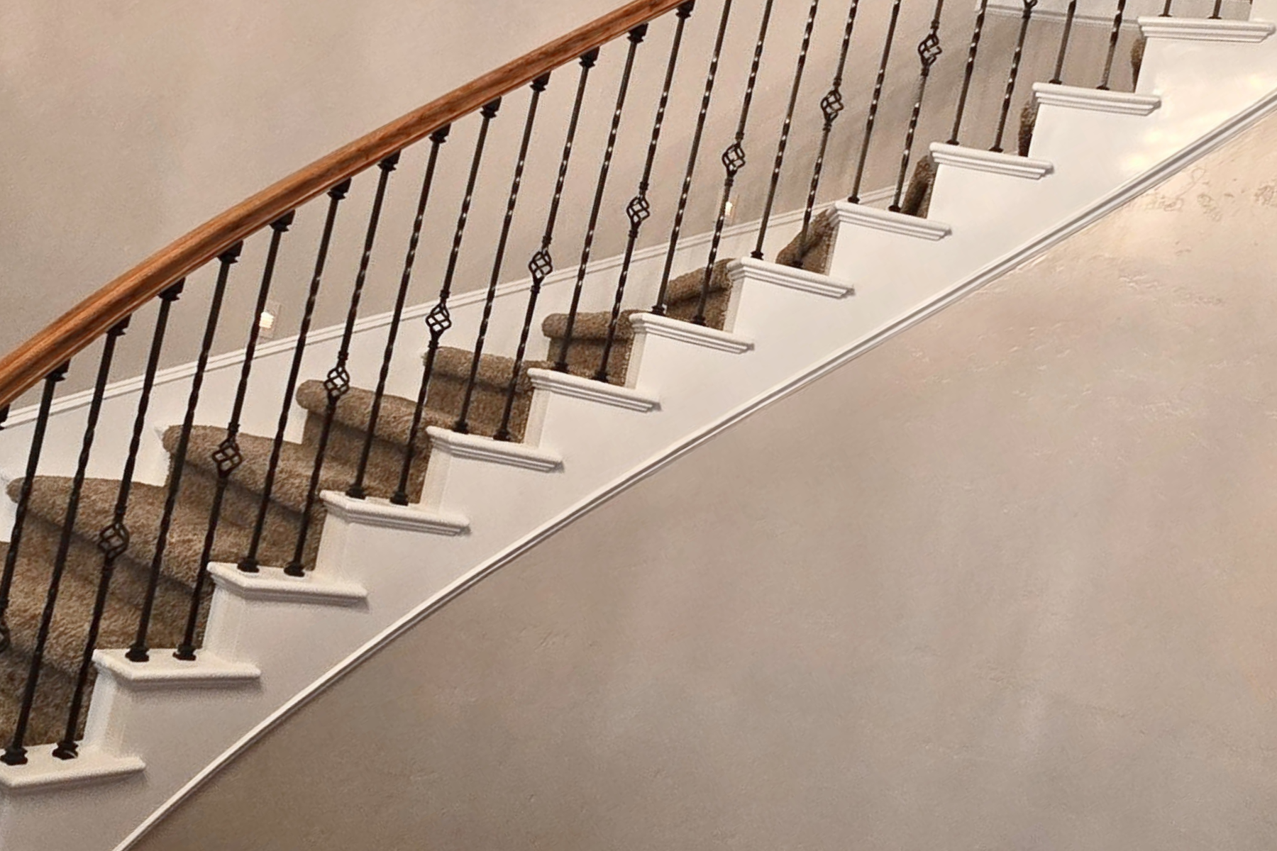 A curved staircase with a wrought iron railing and a carpeted floor.