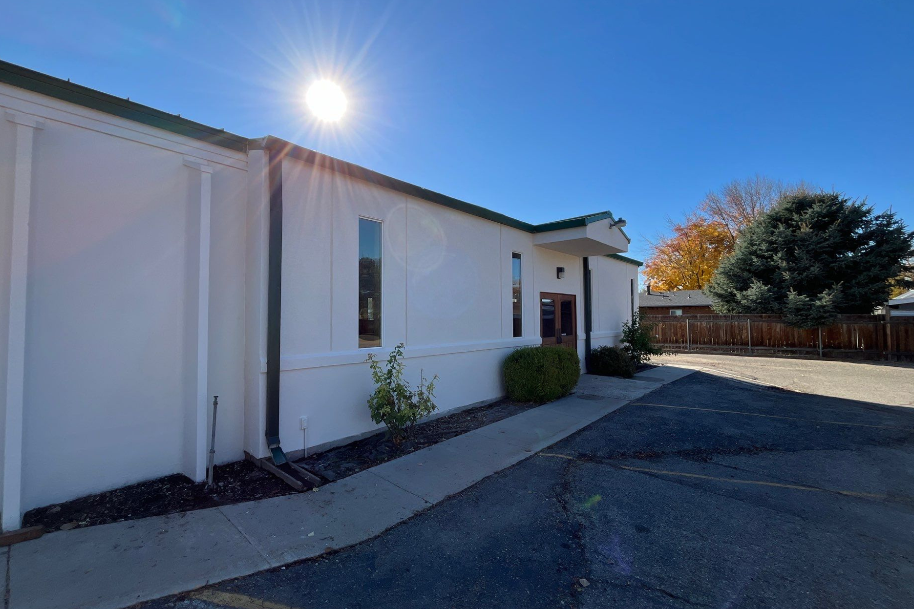 The sun is shining brightly on the side of a white building