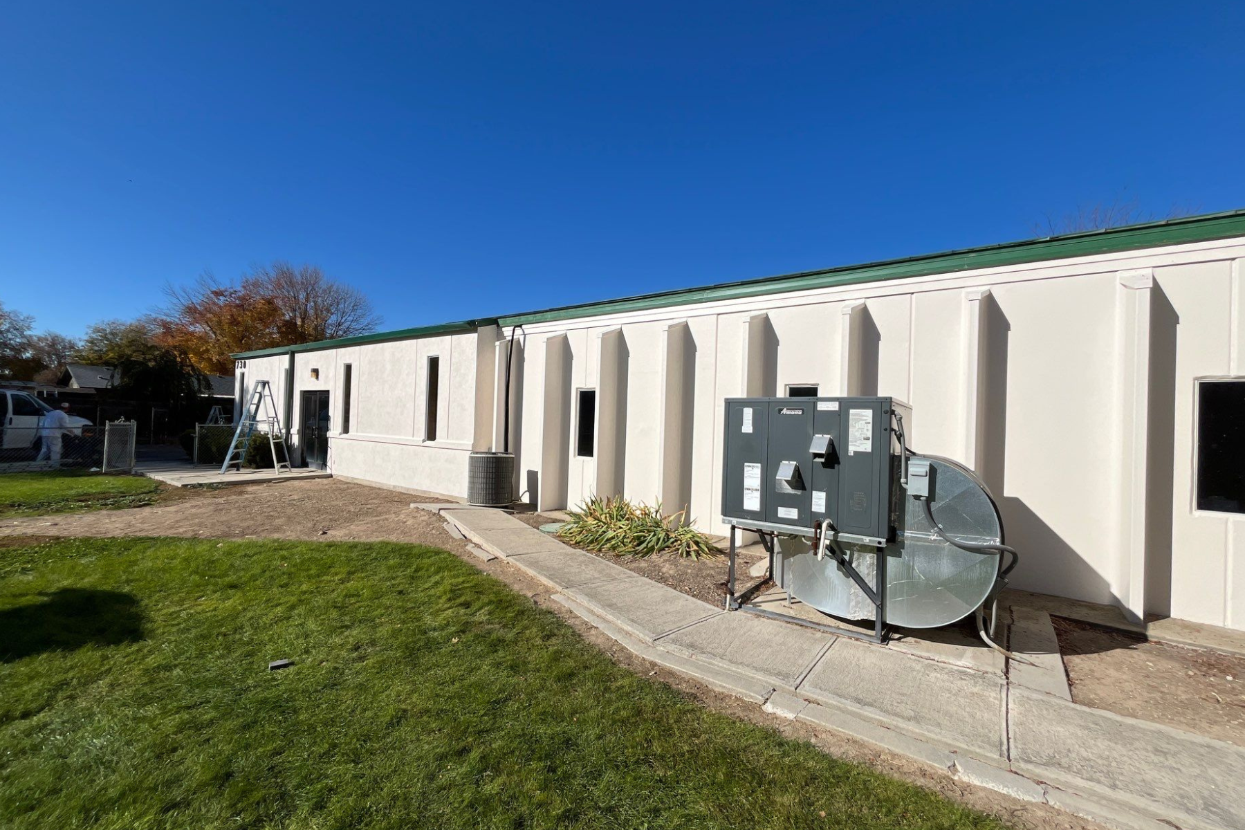 A large white building with a green roof and a satellite dish on the side of it.