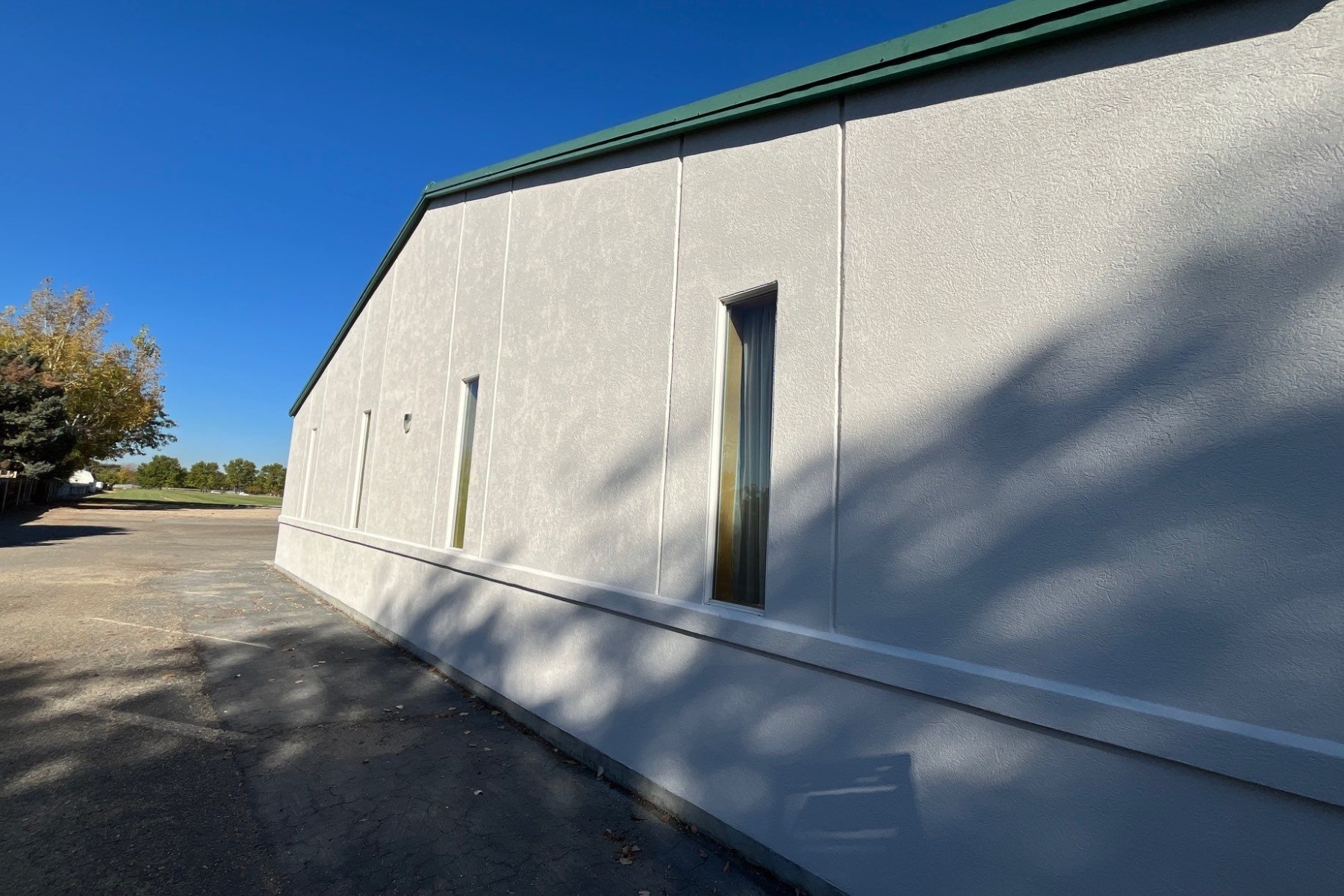 A white building with a green roof and a door