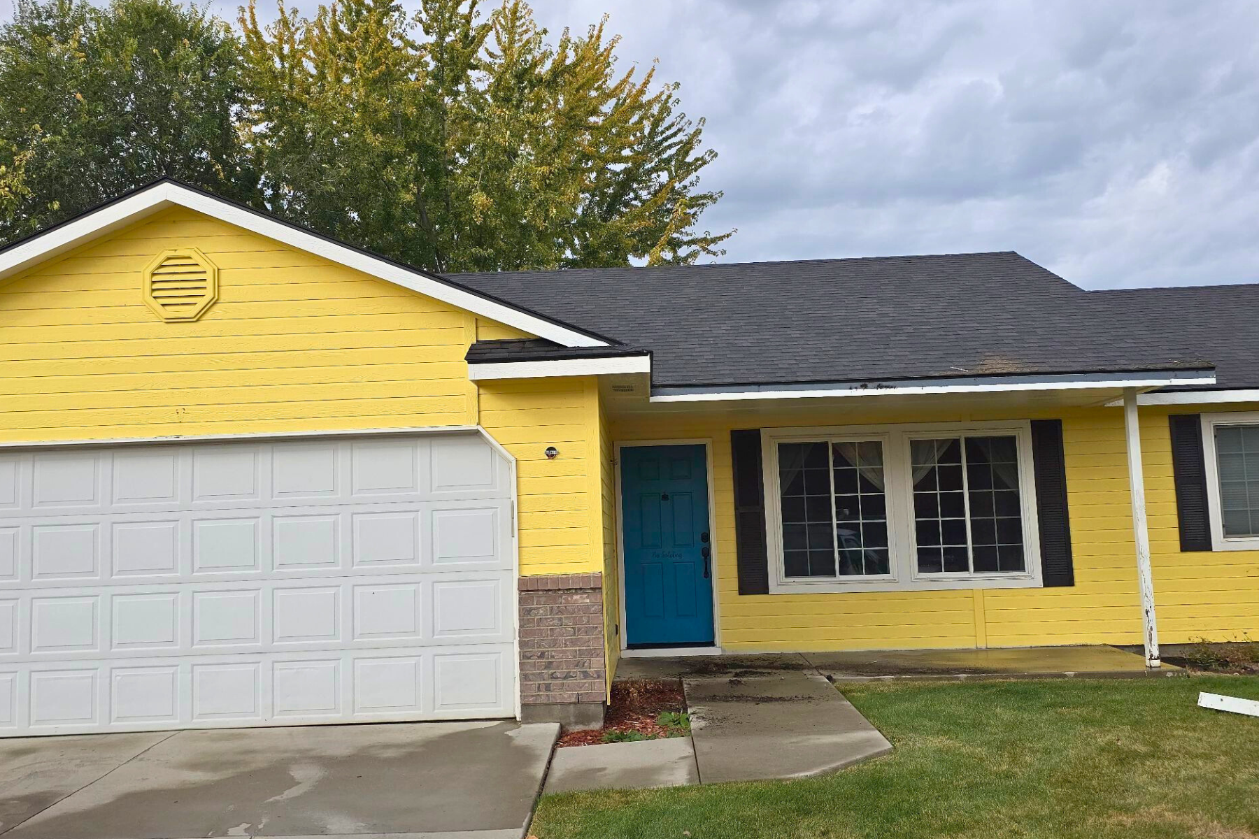 A yellow house with a blue door and a white garage door.