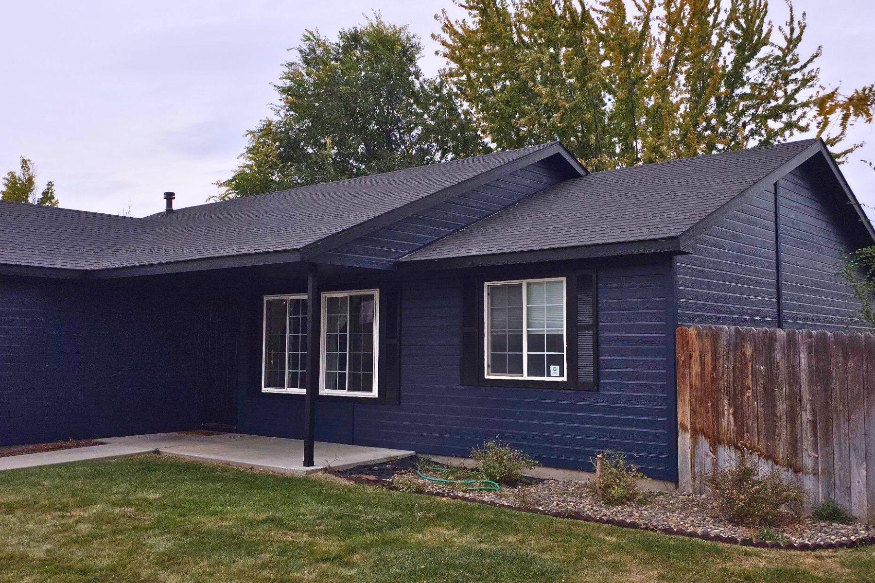 A blue house with a black roof and white windows