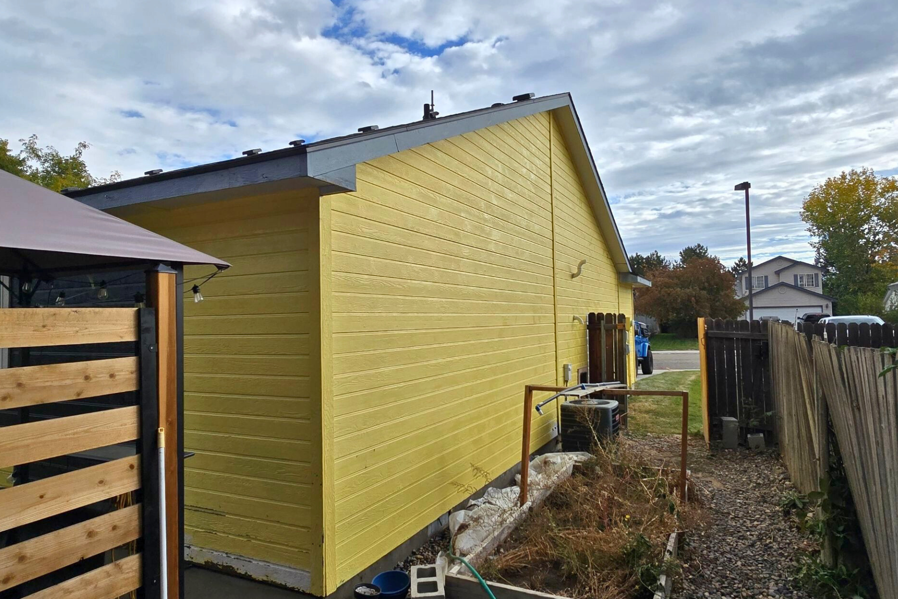 A yellow house with a wooden fence in front of it.