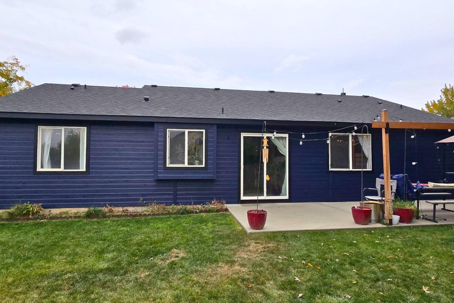 The back of a blue house with a patio and a pergola.