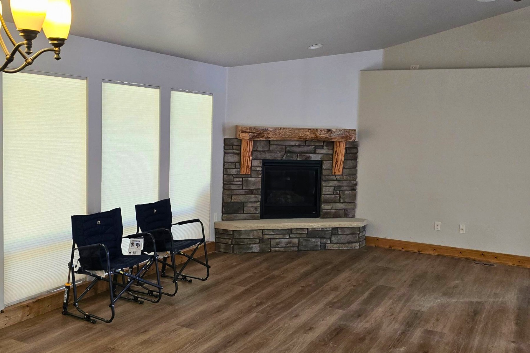 An empty living room with a fireplace and chairs.