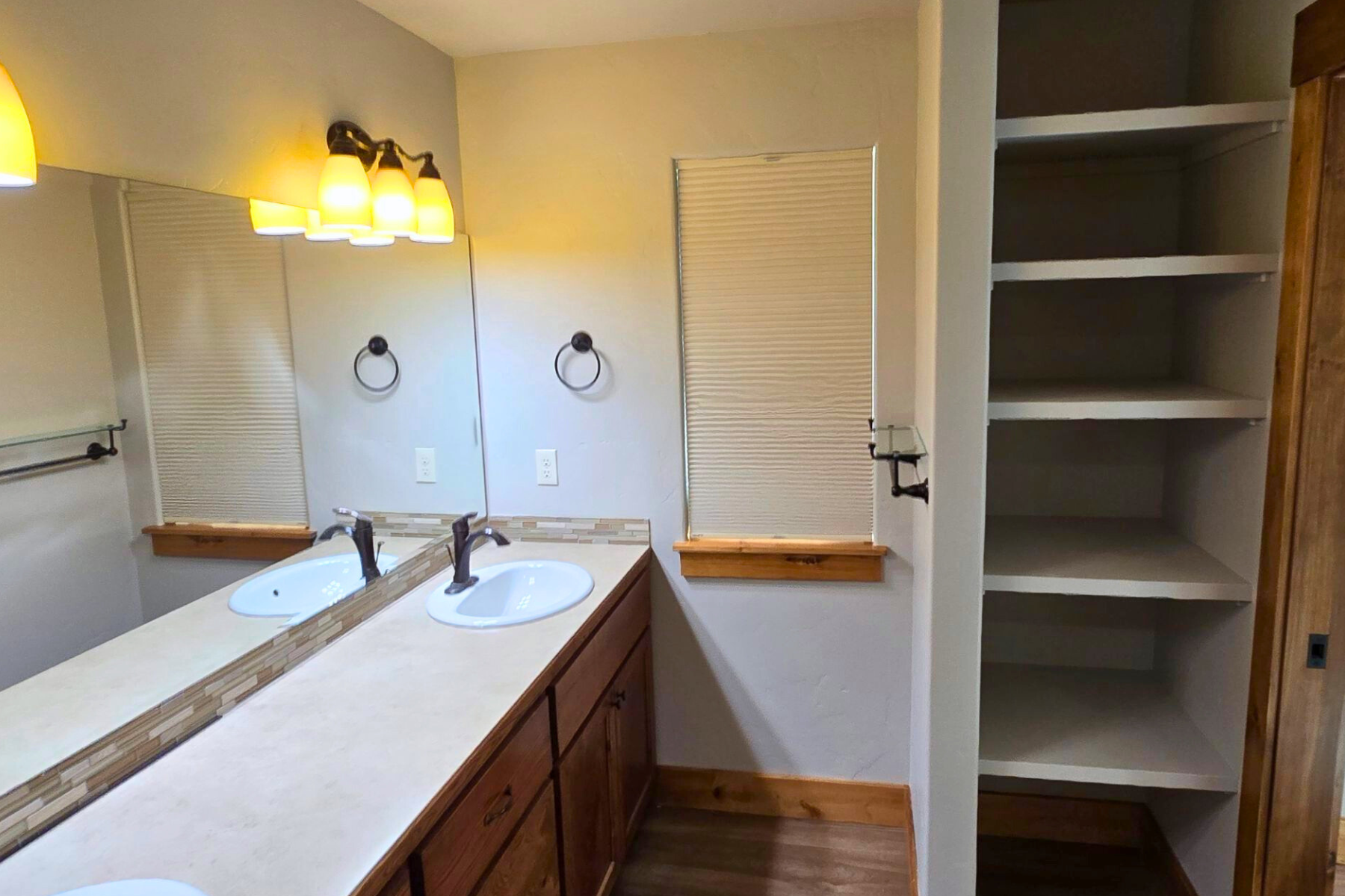 A bathroom with two sinks , a mirror and a closet.