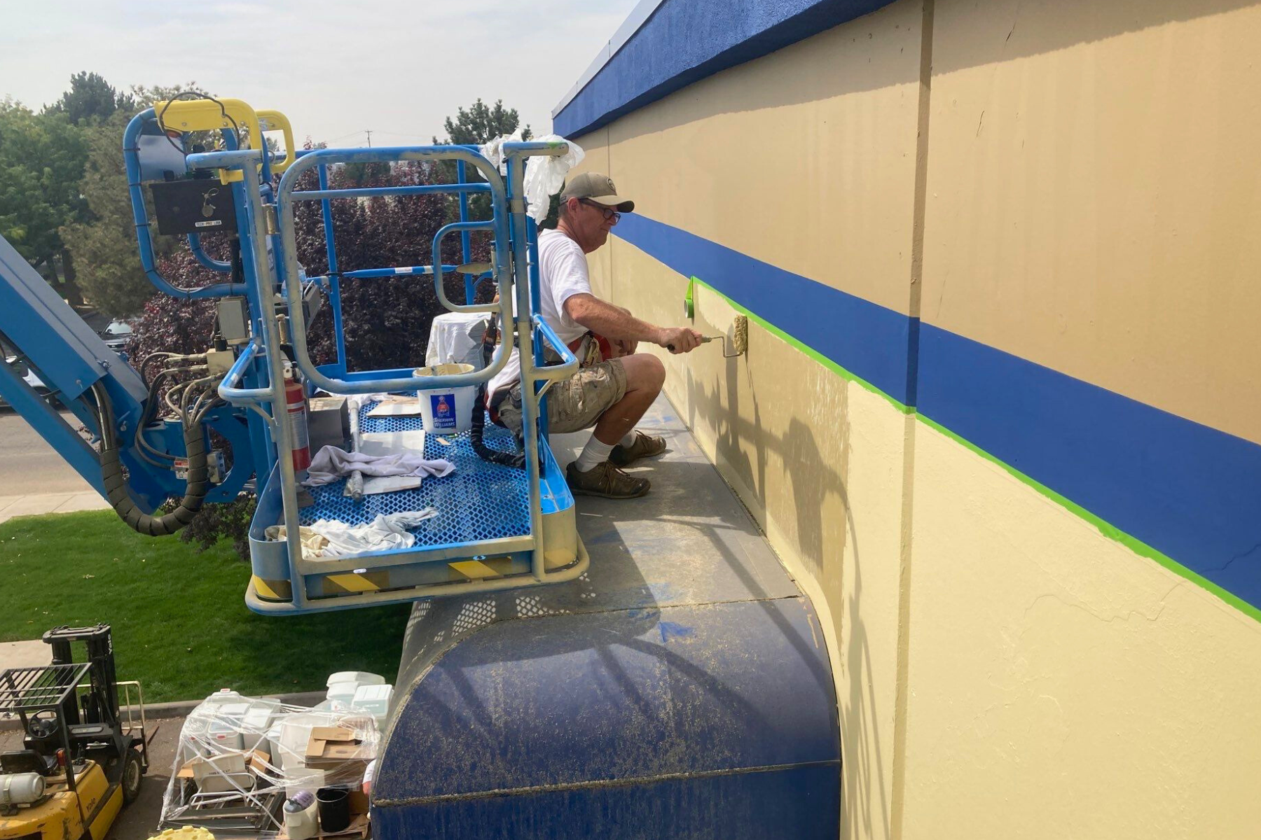 A man is painting a wall on a lift.