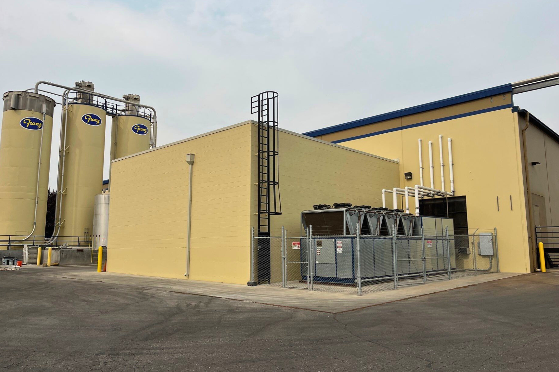 A large yellow building with silos on the side of it.
