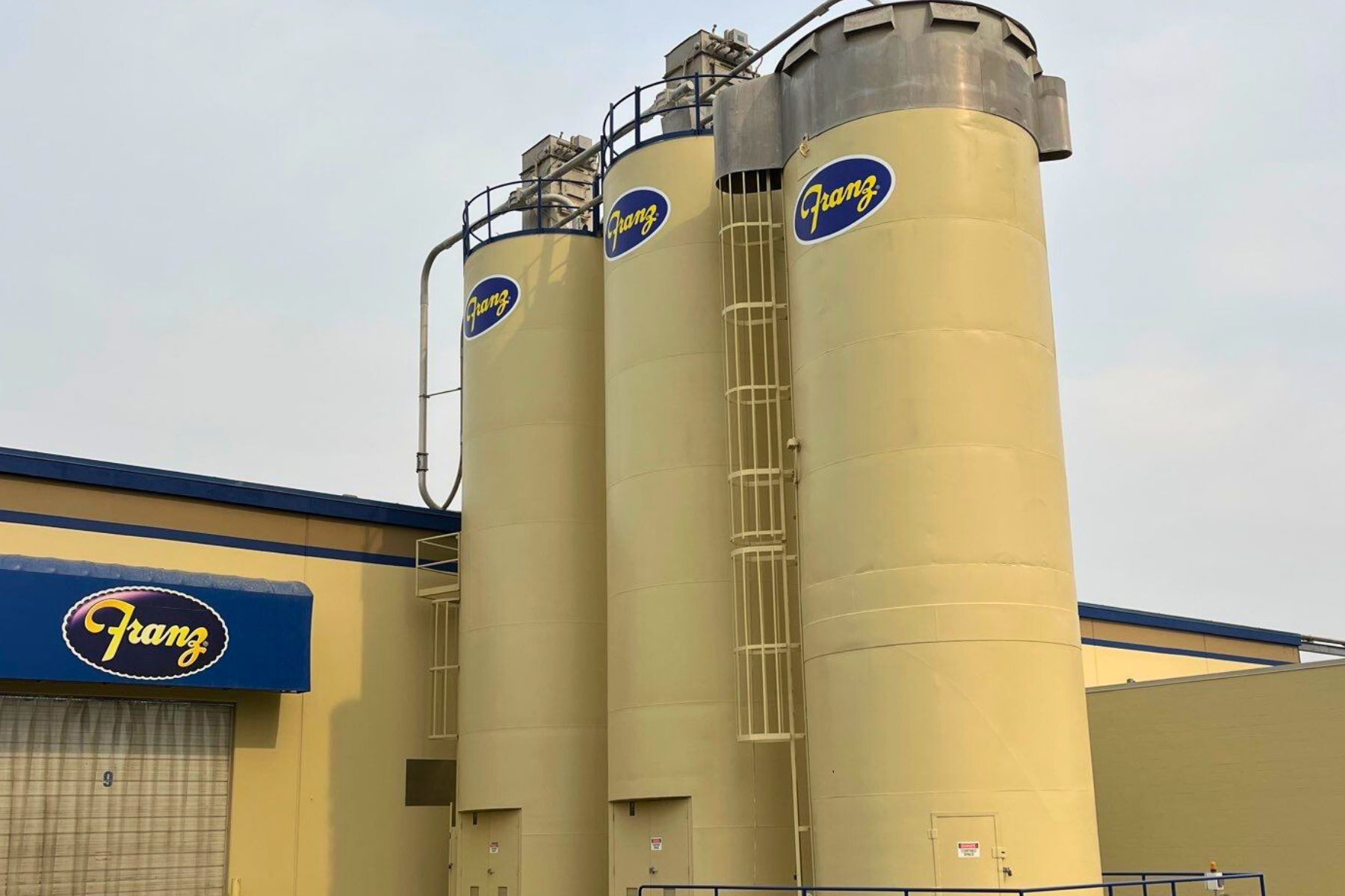 A row of yellow silos are sitting in front of a building.