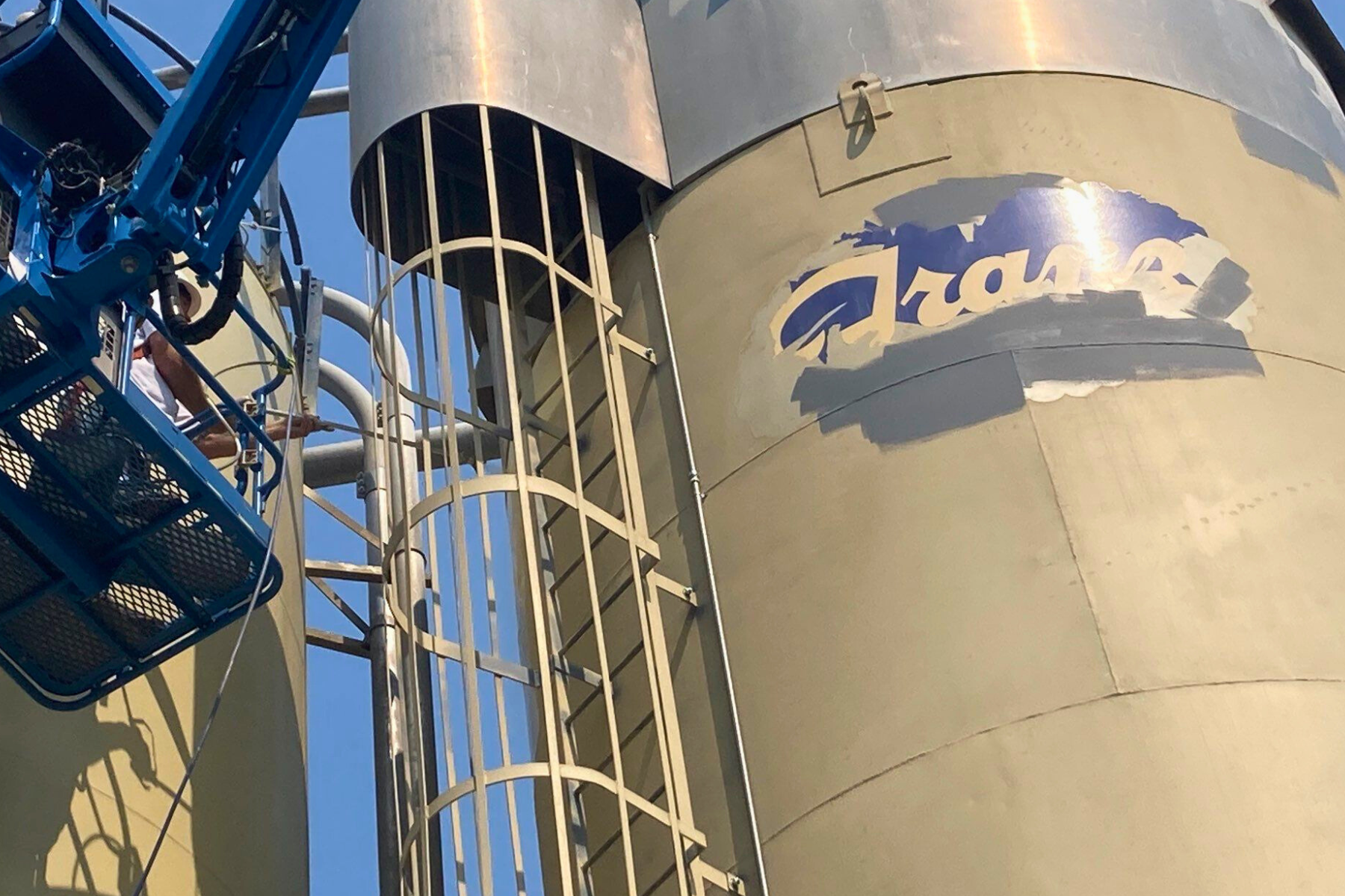 A crane is lifting a large silo that says fraser on it