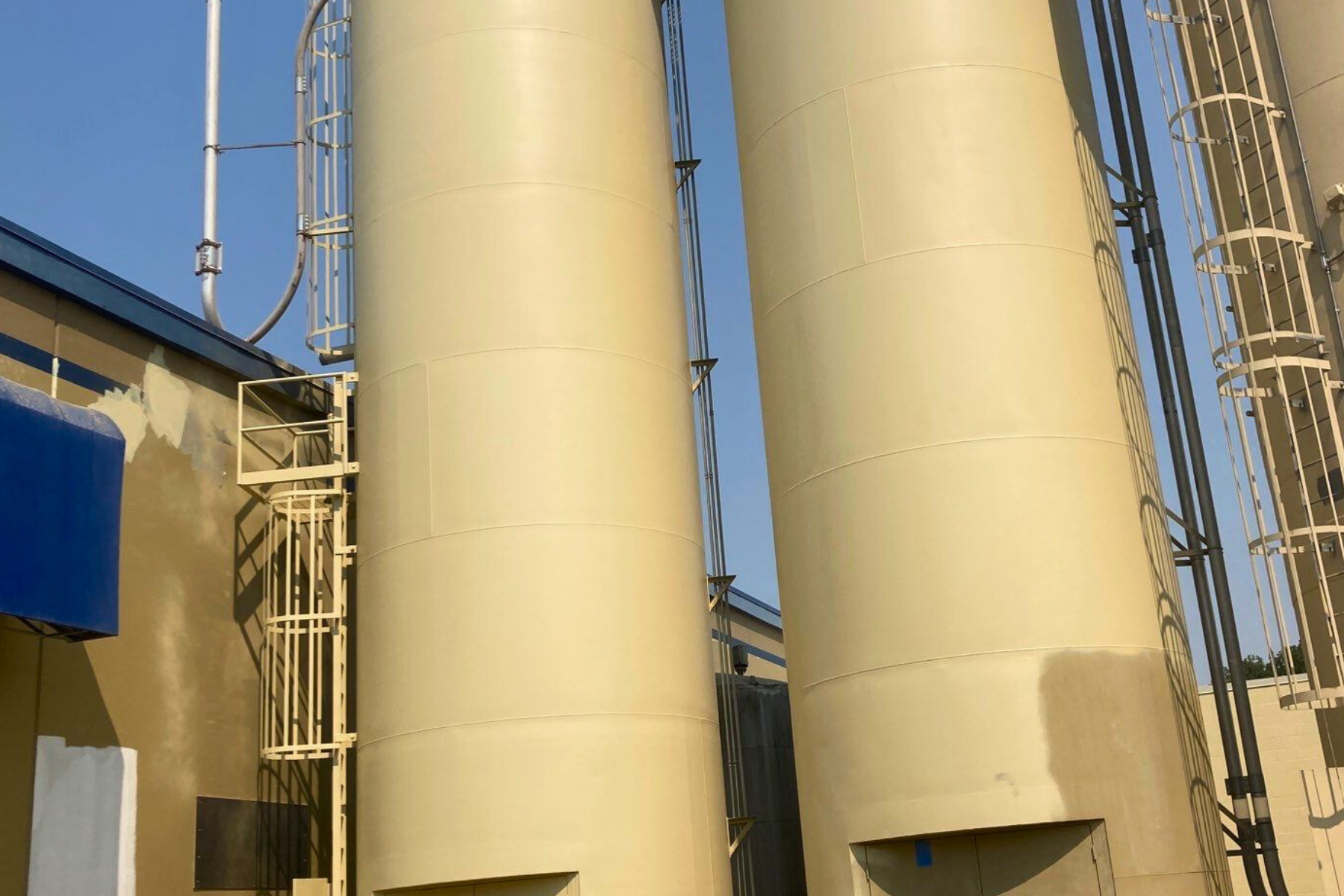 Three large silos are sitting next to each other in front of a building.