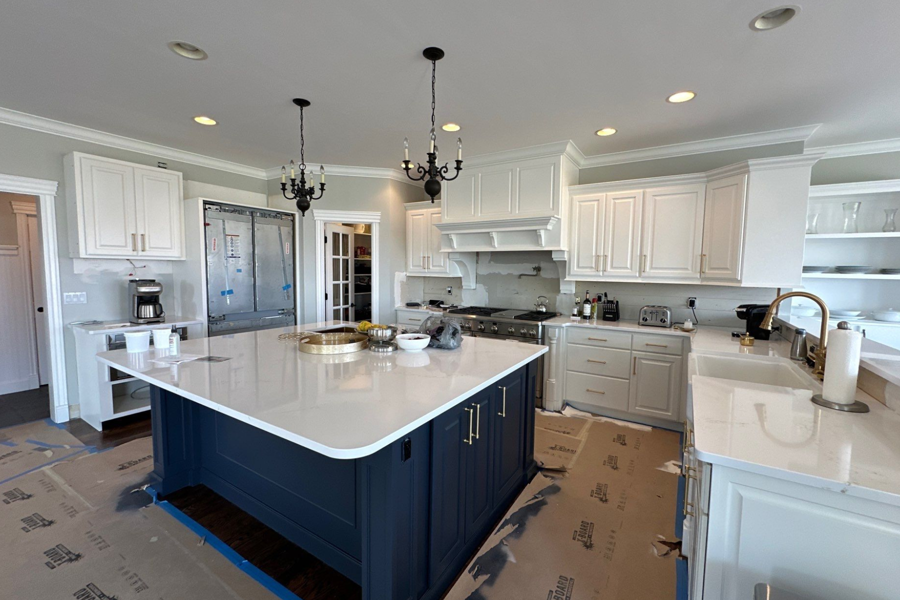 A kitchen with blue cabinets and white counter tops is being remodeled.
