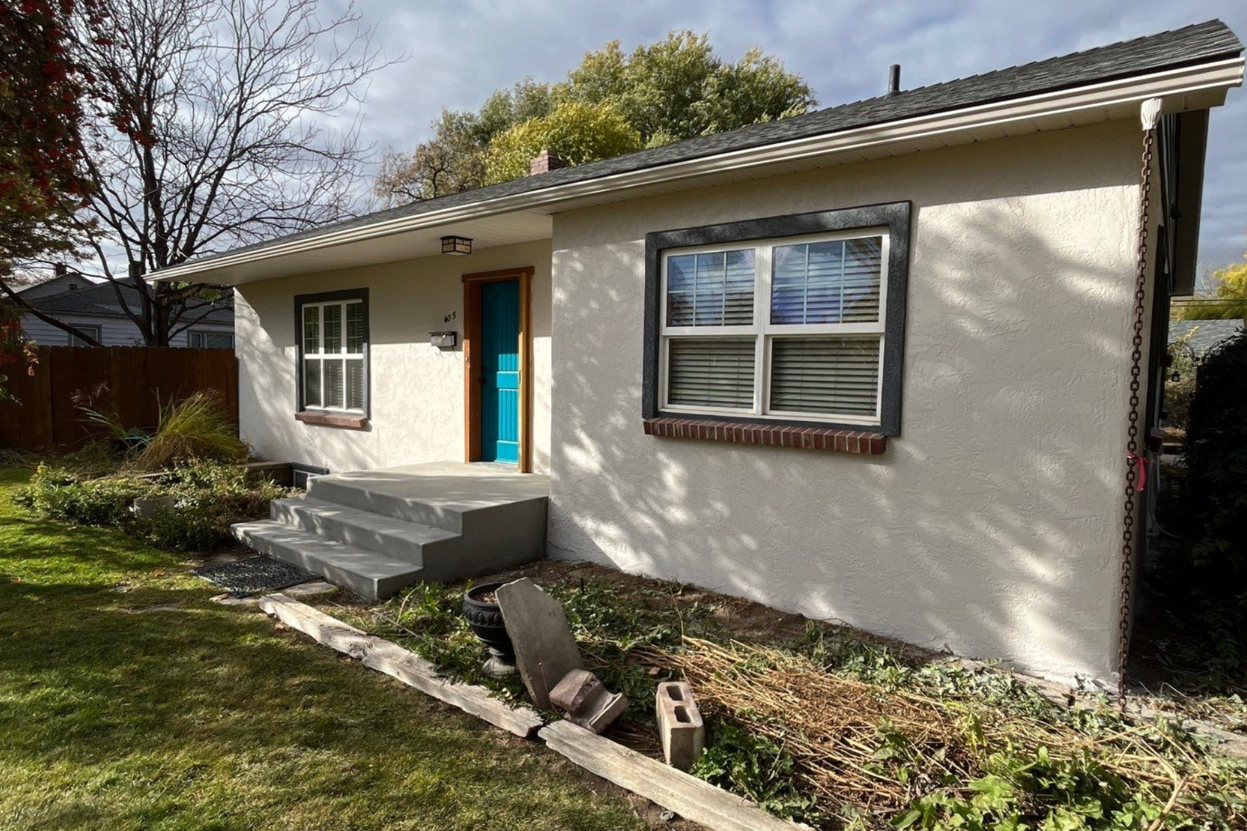 A small white house with a blue door and windows is sitting on top of a lush green lawn.