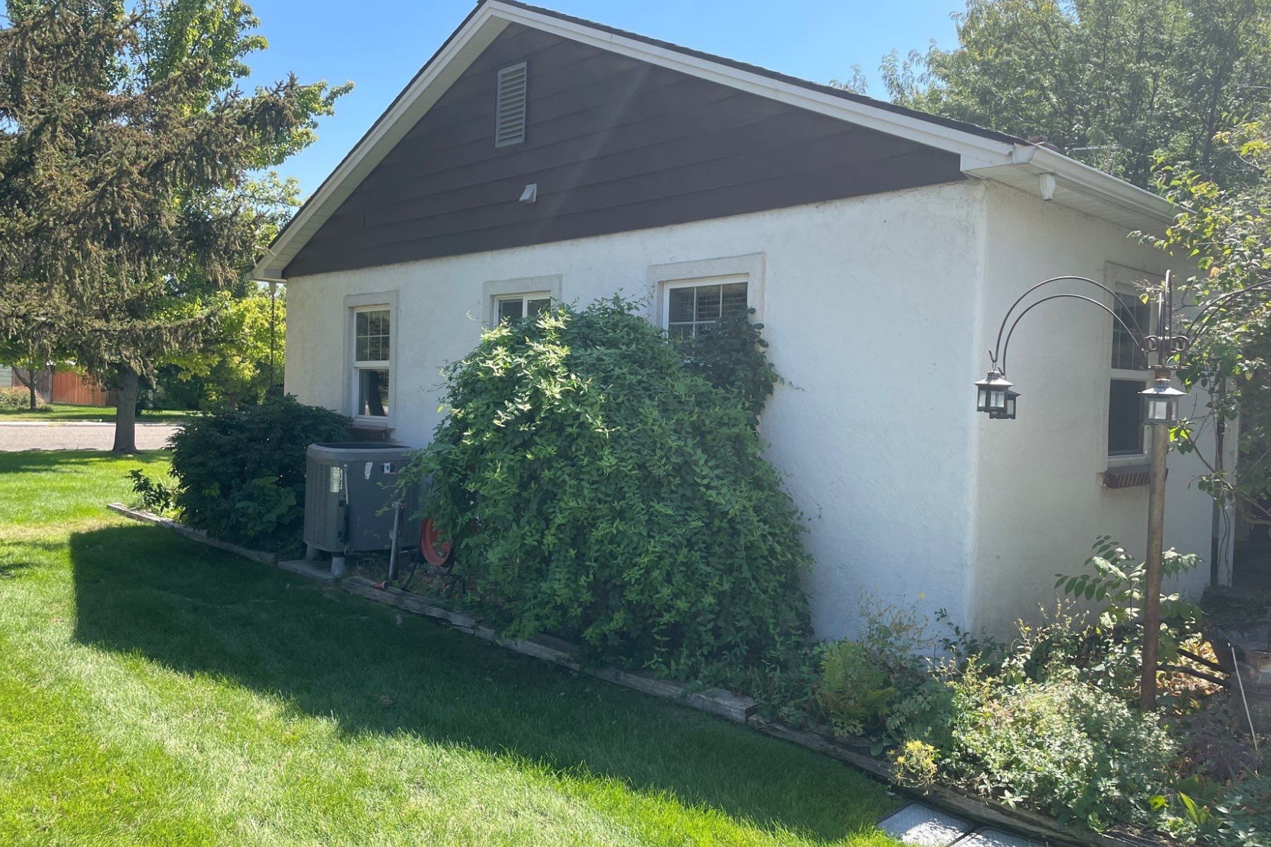 A white house with a brown roof and a bird feeder in front of it.