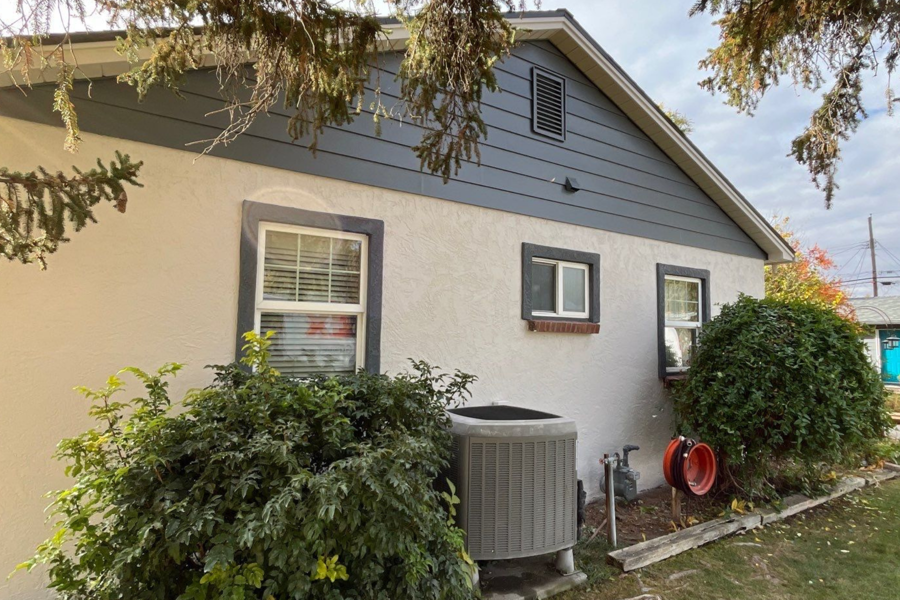 A white house with a gray siding and a gray air conditioner.