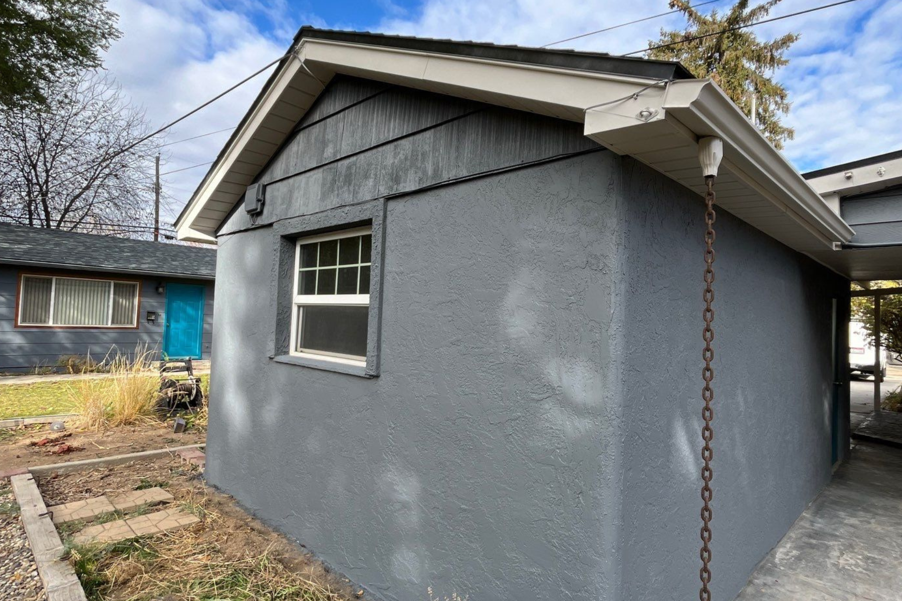 A small gray house with a window and a chain attached to it.